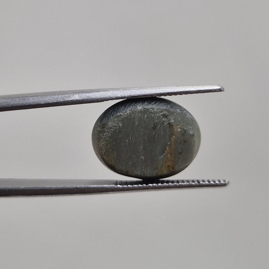 Cat's eye oval cabochon gemstone viewed from a second angle showing its greenish grey body colour