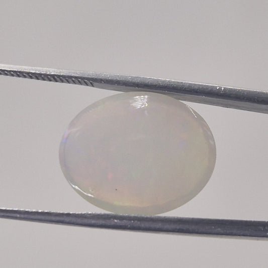 Opal oval cabochon gemstone from a second angle showing its translucency and domed profile
