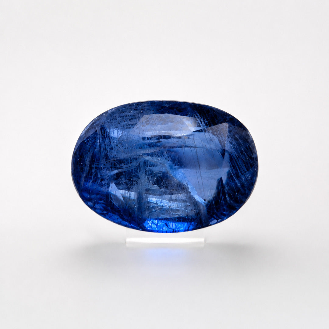 Blue sapphire oval cut gemstone photographed face-up against a pale background