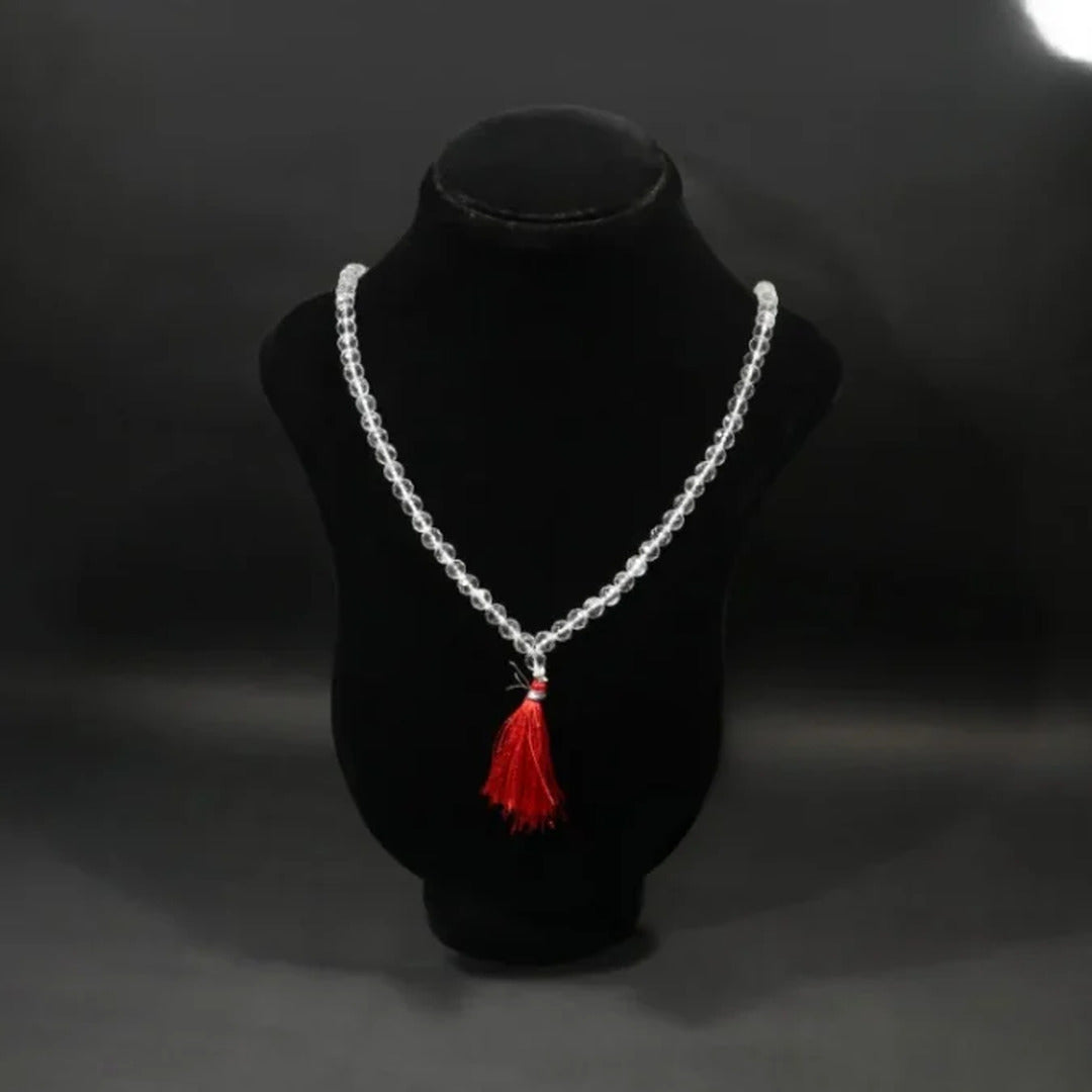 Clear crystal beaded mala finished with a red thread tassel, displayed on a black velvet bust