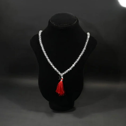 Clear crystal beaded mala finished with a red thread tassel, displayed on a black velvet bust