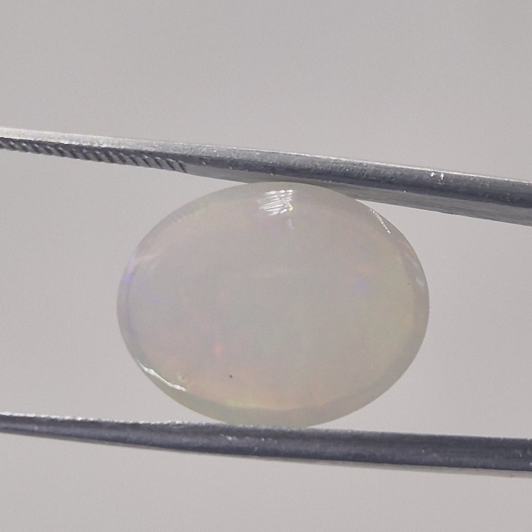 Opal oval cabochon gemstone from a second angle showing its translucency and domed profile